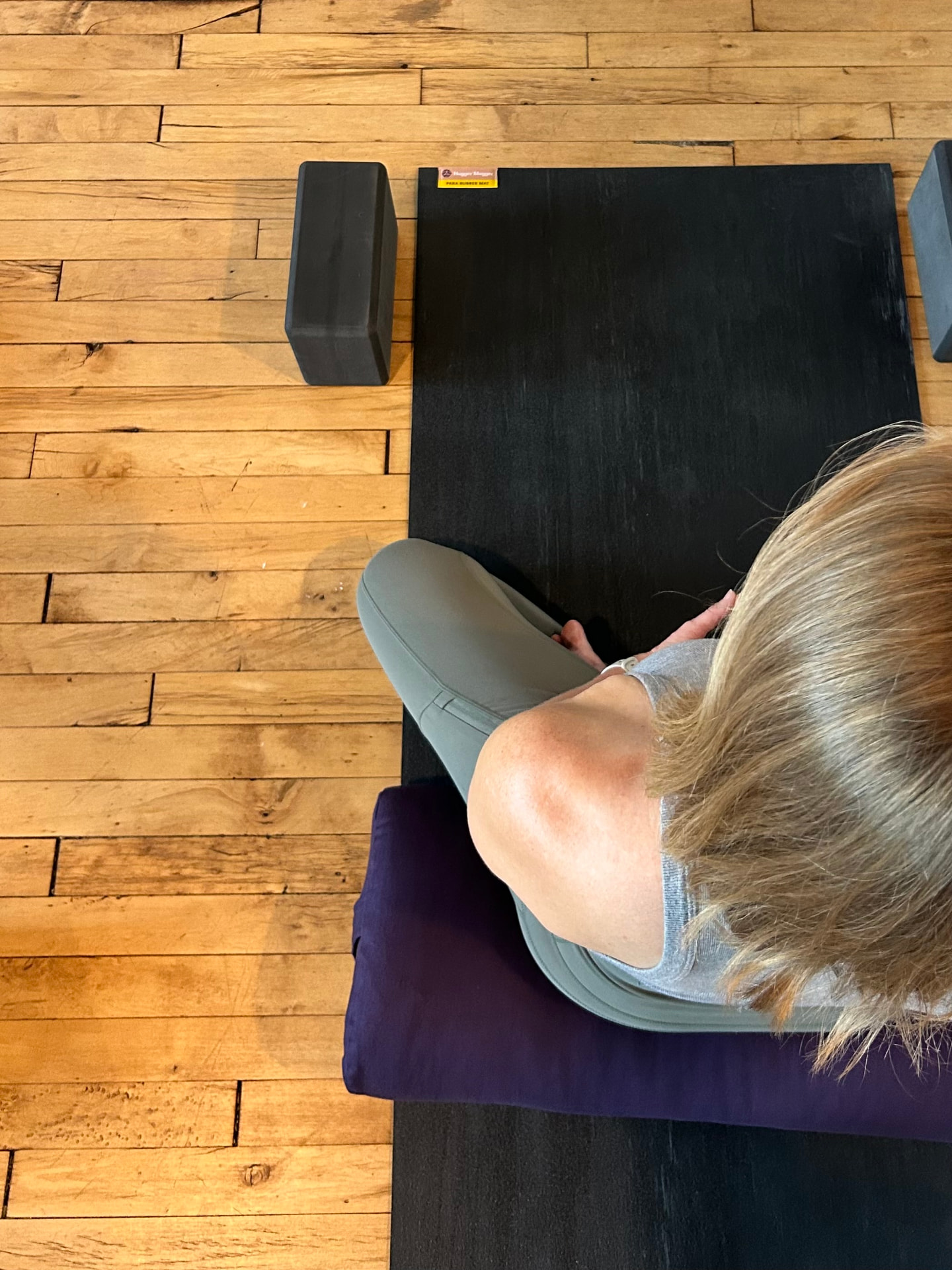 A student seated in quiet practice on a yoga mat, seen from above